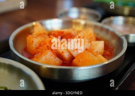 Kimchi de radis coréen, kkakdugi, un plat d'accompagnement épicé fermenté populaire servi dans un bol en métal. Banque D'Images
