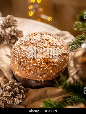 Délicieux panettone de Noël italien décoré de sucre perlé, placé sur un fond d'arbre de Noël décoré avec des ornements lumineux et pi Banque D'Images