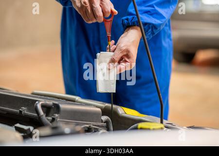 Gros plan d'un mécanicien automobile vérifiant le niveau d'huile dans un atelier mécanique Banque D'Images