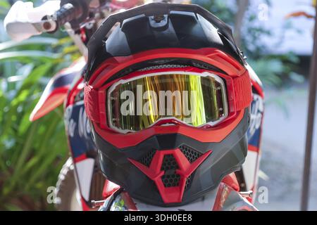 Vue rapprochée montrant un casque de motocross avec des lunettes de protection reflétant la nature poignée de vélo de terre montrant la disponibilité pour la conduite aventureuse en plein air se Banque D'Images