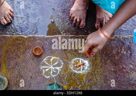 Inde. État de l'Uttar Pradesh. Varanasi (Benares). Des pélerins effectuent un rituel de création de motifs sacrés au sol (rangoli ou kolam) avec de la Banque D'Images