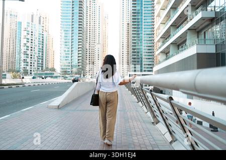 Voyageur seul marchant dans la rue de la ville de Singapour entourée de bâtiments de grande hauteur, vue en angle bas des grands immeubles résidentiels et de bureaux Banque D'Images