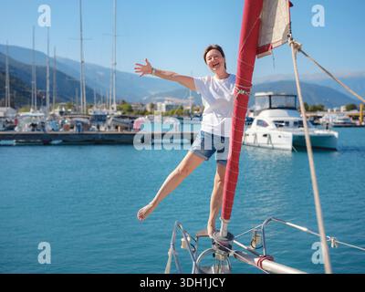 Femme marin tient le tissu de voile blanc se préparant à lever des voiles sur le yacht. L'activité physique et les compétences de manœuvre de bateau sont montrées pendant la préparation à l'as Banque D'Images