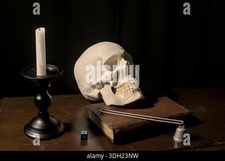 Memento Mori Still Life avec un crâne humain, une bougie et un vieux livre sur fond sombre Banque D'Images