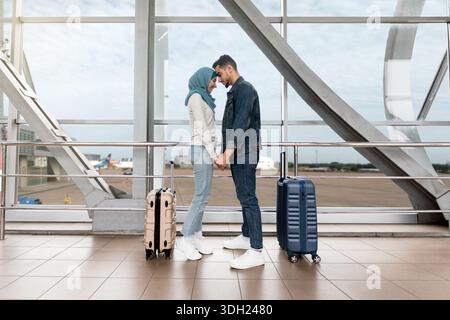 Portrait d'un couple islamique aimant qui colle à l'aéroport tout en attendant le vol Banque D'Images