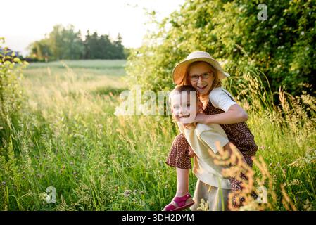 Frères et sœurs debout dans de grandes herbes au coucher du soleil. Heure du printemps. Banque D'Images