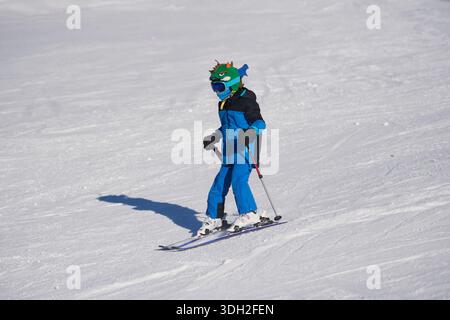 Enfant apprenant à skier sur une pente enneigée dans une station de ski. Enfant portant casque et vêtements d'hiver aime les sports d'hiver en plein air. Vacances actives en famille, w Banque D'Images