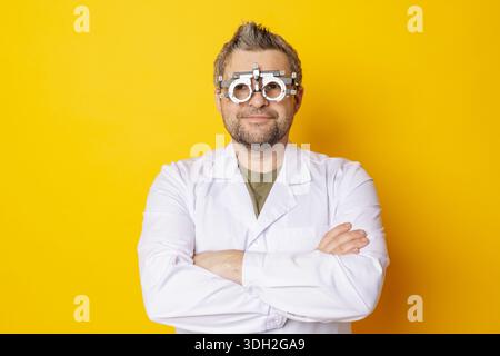 Optométriste masculin portant monture d'essai pour le concept de réfraction et de correction de la vision pour la prescription de lunettes ou de lentilles de contact sur fond jaune Banque D'Images