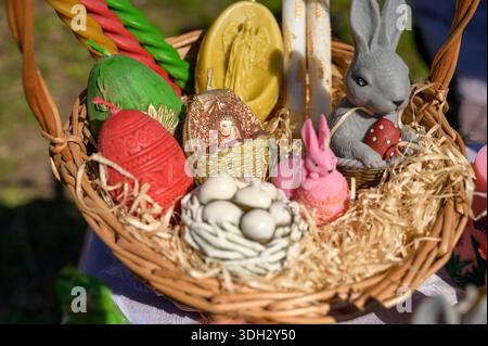 Panier en osier rempli de bougies de Pâques décoratives faites à la main en forme d'œufs et de lapins en Europe. Concept de décoration de table de vacances festive, artisanale Banque D'Images