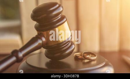 Un marteau de juge et deux anneaux de mariage sur une surface en bois, symbolisant le divorce ou les procédures judiciaires liées au mariage. Banque D'Images