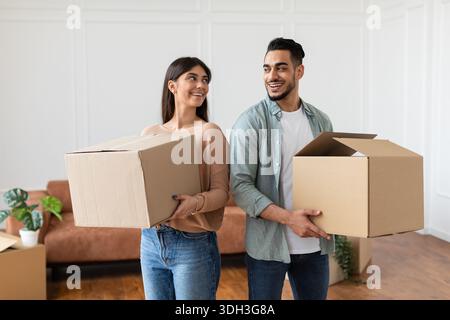 Couple millénaire heureux tenant des boîtes en carton, concept de relocalisation Banque D'Images