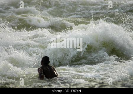Un homme nage courageusement à travers les rapides du Nil à Jinja, Ouganda, naviguant dans les eaux vives mousseuses et les puissants courants de l'un d'entre eux Banque D'Images