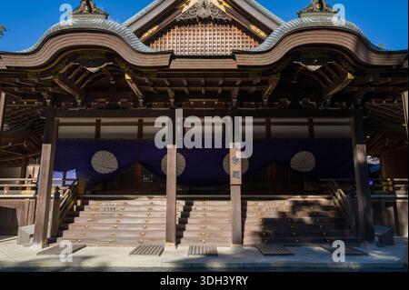 ISE, Japon - 29 octobre 2023 : la façade avant de la salle Kaguraden à ISE Jingu est représentée avec une architecture traditionnelle en bois, des détails de toit ornés et des draperies violettes avec des emblèmes blancs au-dessus des marches d'entrée. Banque D'Images