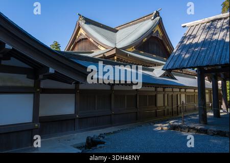 ISE, Japon - 29 octobre 2023 : le côté de la salle Kaguraden à ISE Jingu est visible avec une architecture traditionnelle en bois, des toits en tuiles inclinées et des éléments décoratifs dorés sous un ciel bleu clair. Banque D'Images