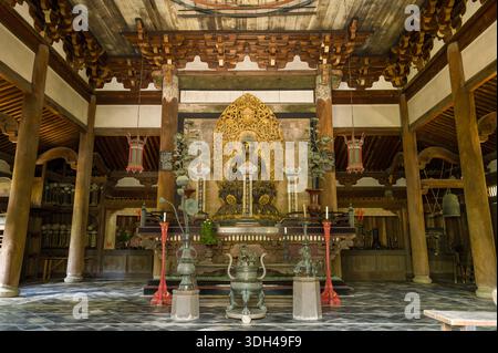 Kyoto, Japon - 17 octobre 2023 : L'intérieur du Daitoku-ji Butsuden présente une statue centrale de Bouddha sur un autel orné, entourée d'objets rituels, de colonnes en bois, de lanternes suspendues et de détails architecturaux traditionnels. Banque D'Images