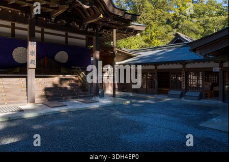 ISE, Japon - 29 octobre 2023 : la cour et l'entrée du hall Kaguraden à ISE Jingu sont présentées avec une architecture traditionnelle en bois, des draperies violettes avec des emblèmes blancs et des éléments décoratifs dorés sous la lumière du soleil. Banque D'Images
