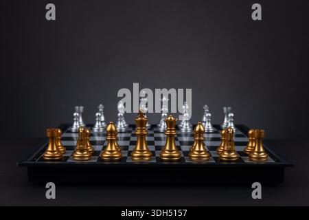 échiquier avec des pièces d'échecs prêtes pour le jeu sur fond sombre. Banque D'Images