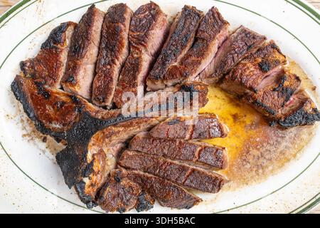 Vue de dessus d'un succulent steak parfaitement grillé coupé en tranches et servi sur une assiette blanche, avec des jus riches coulant, mettant en valeur l'appétissant exter carbonisé Banque D'Images