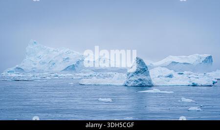 De majestueux icebergs flottent sereinement dans les eaux froides et bleues du Groenland. La toile de fond sereine du paysage arctique met en valeur le magnifique, texturé Banque D'Images
