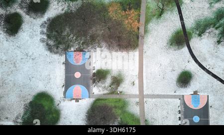 Vue drone sur le terrain de basket-ball extérieur et le parc couvert de neige Banque D'Images