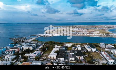 Vue aérienne des bâtiments modernes rencontre les eaux tranquilles du lagon à Lekki, avec des nuages reflétant le bord de l'eau, Lekki, Lagos, Nigeria. Banque D'Images