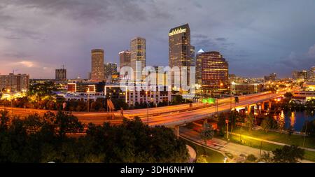 Centre-ville de Tampa ville en Floride, États-Unis. Circulation automobile sur le pont autoroutier au-dessus de la rivière Hillsborough et hauts gratte-ciel illuminés Banque D'Images