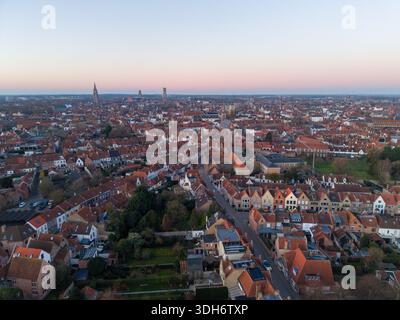 Vue aérienne de la vieille ville avec des toits rouges et de hautes flèches atteignant le ciel, projetant de longues ombres dans la lumière de décoloration, Bruges, Flandre, Belgi Banque D'Images