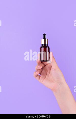Flacon de sérum dans les mains féminines, vue de dessus. Hydratant transparent pour les soins de la peau. Huile essentielle nourrissante en flacon en verre avec pipette. Emulsion liquide Banque D'Images
