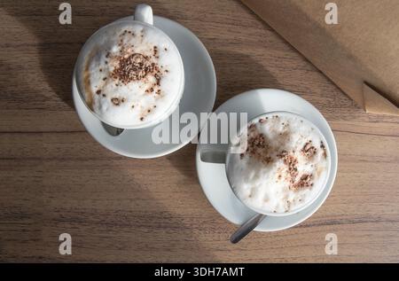 Deux tasses de cappuccino avec mousse de lait et cacao sur une table en bois Banque D'Images