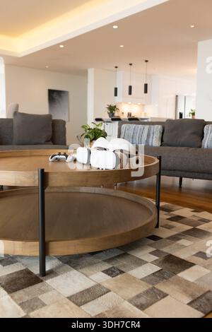 La table basse ronde en bois à deux niveaux tient un casque VR blanc et un contrôleur sur le tapis près de la cuisine Banque D'Images