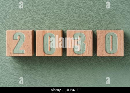 Cubes en bois avec les numéros 2030 sur fond vert. Concept de planification future et objectifs à long terme Banque D'Images