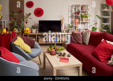 Salon décoré pour les vacances Tet avec des ornements festifs, des plateaux de fruits, des collations et des éléments traditionnels disposés sur la table et les étagères avec des sièges et des plantes vibrants Banque D'Images