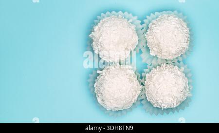 Quatre boules de noix de coco blanches dans une rangée. Les boules sont dans des gobelets en papier blanc Banque D'Images