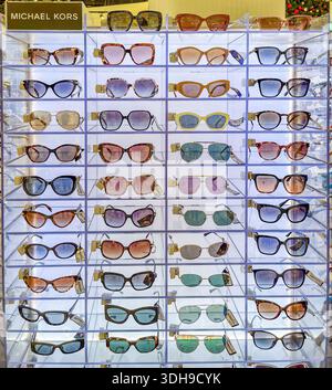Malaga, Espagne - 21 décembre 2025 : lunettes de soleil Michael Kors disposées sur un présentoir transparent, avec plusieurs couleurs et styles dans un environnement de vente au détail Banque D'Images