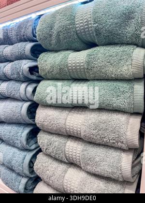 Des serviettes douces dans les tons de bleu et de vert sont soigneusement empilées sur une étagère, soulignant leur texture et les variations de couleur avec un espace de copie disponible pour d Banque D'Images