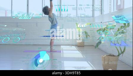 Femme debout portant un débardeur gris, un short bleu, levant les bras dans un loft avec un tapis violet et des hologrammes Banque D'Images