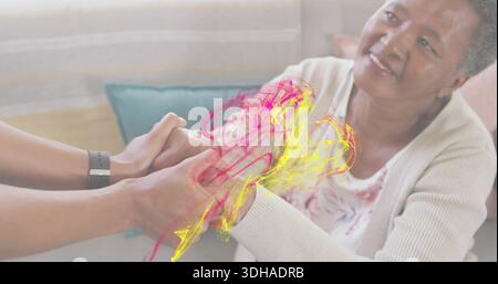 Tenant la femme adulte moyenne soutenant les mains de la femme âgée sur le canapé à la maison avec la montre, tourbillons magenta Banque D'Images