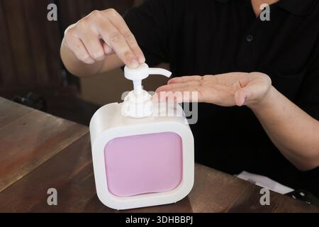 Gros plan femelle distributeur de savon à pompe à main pour nettoyer soigneusement les doigts pour la protection contre les bactéries et les infections virales sur la table en bois, concentré an Banque D'Images