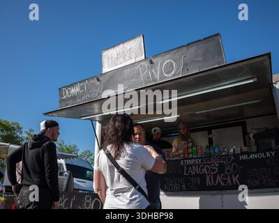 Les gens qui achètent de la bière et de la nourriture comme des langos et des frites à partir d'un food truck de rue très fréquenté lors d'un événement en plein air lors d'une journée ensoleillée en République tchèque Banque D'Images
