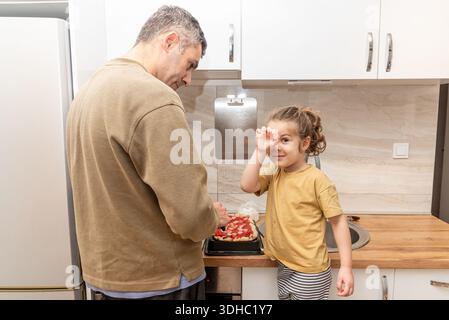 Homme de famille et fille cuisinant des pizzas maison dans la cuisine, papa et fille passant du temps ensemble Banque D'Images