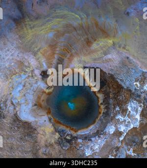 Vue aérienne d'un paysage surréaliste et surréaliste où une piscine turquoise dynamique reflète le ciel au milieu de motifs tourbillonnants d'ocre et de bleus glacés, HVO Banque D'Images