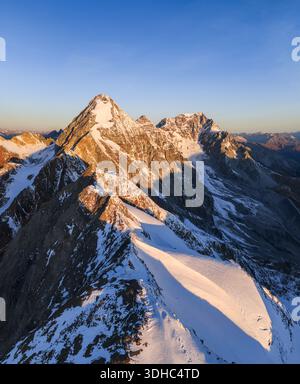 Vue aérienne des sommets de montagne enneigés touchés par la lueur chaude du soleil couchant, projetant de longues ombres à travers le paysage glacé, Gran Zebru, Lom Banque D'Images