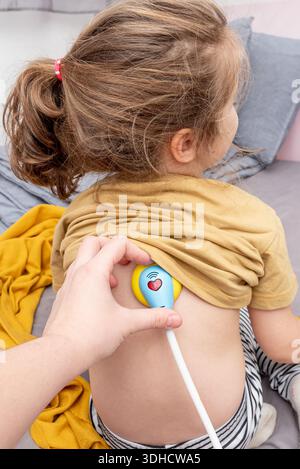 Maman et fille jouant médecin imaginaire, femme écoutant stéthoscope fille tout-petit Banque D'Images