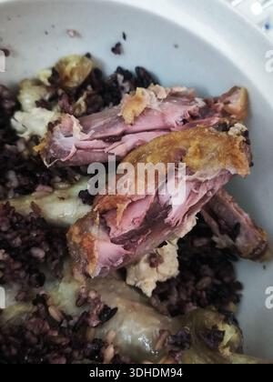 Gros plan de poulet rôti avec du riz noir dans un bol Banque D'Images