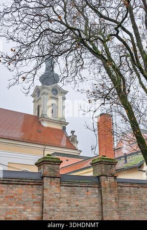 Une tour de l'horloge historique s'élève au-dessus des toits chauds en tuiles rouges. L'église des Saints Eusèbe et Polion est une église catholique romaine de Vinkovci, en Croatie. Banque D'Images