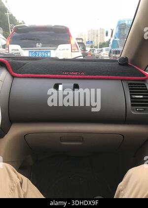 Vue intérieure du tableau de bord d'une voiture Honda avec garniture rouge, montrant la circulation devant le conducteur Banque D'Images
