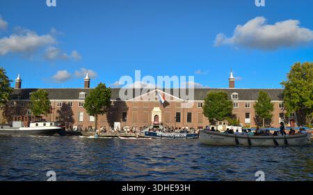Le musée d'art Hermitage Amsterdam, situé sur la rivière Amstel, avec des bateaux touristiques et des visiteurs à Amsterdam, aux pays-Bas. Photographié en 2023. Banque D'Images