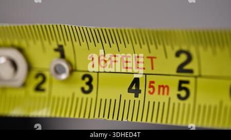 Vue macro d'un mètre à ruban rétractable métallique montrant les incréments en pieds et métriques Banque D'Images