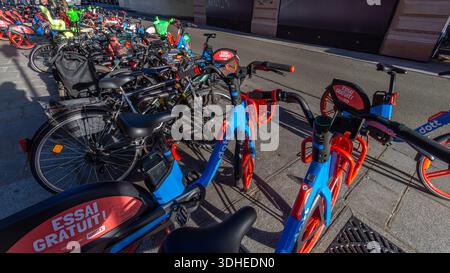De nombreux vélos en libre-service appartenant à différents services de location de vélos sans quai et de mobilité partagée stationnés dans une rue de Paris, France Banque D'Images