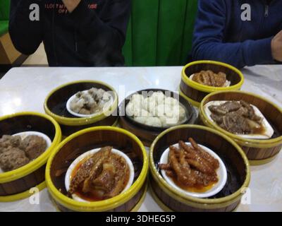 Une variété de plats dim sum servis dans des cuiseurs à vapeur en bambou sur une table à manger Banque D'Images